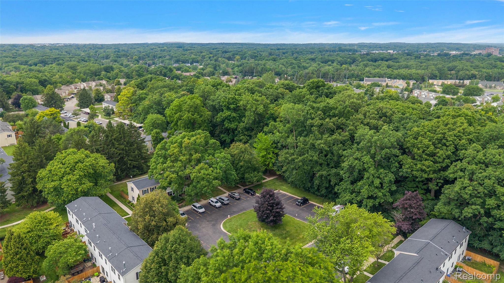 930 Little Hill Court Rochester, MI 48307 - Photo 15 of 38 Expansive treed landscape featuring multiple multi-unit buildings, paved parking areas, and mature greenery