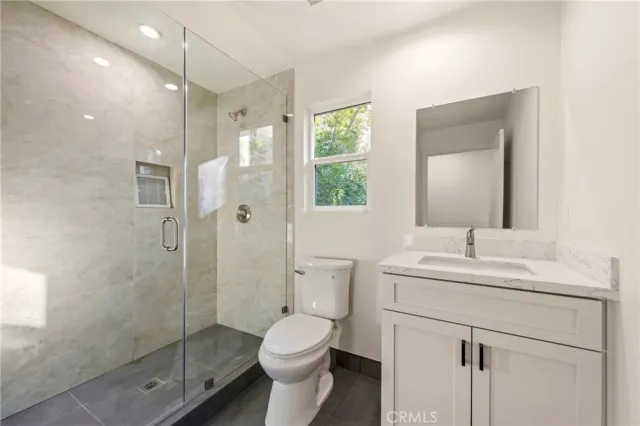 a bathroom with a shower sink vanity mirror and toilet
