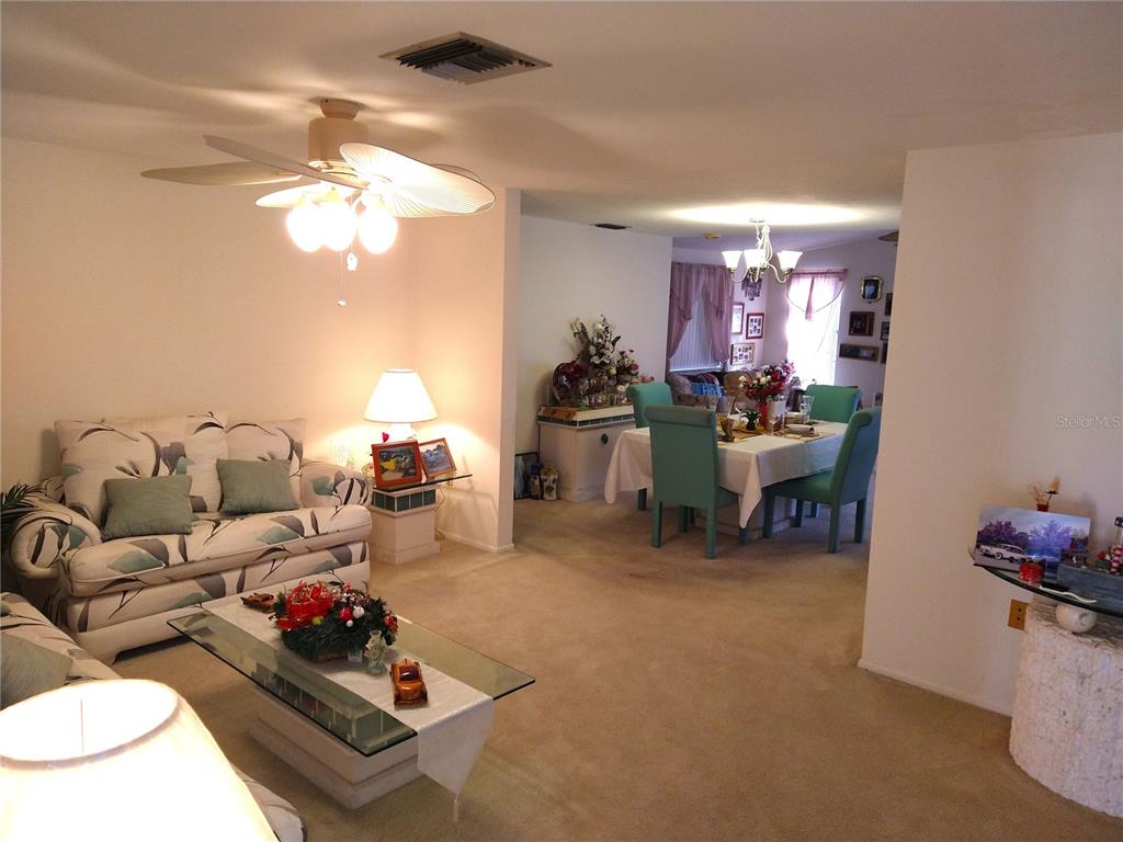 8415 Briarleaf Court Port Richey, FL 34668 - Photo 5 of 27 a living room with furniture a chandelier and a wooden floor