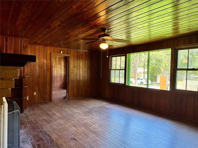 a view of an empty room with a window and wooden floor