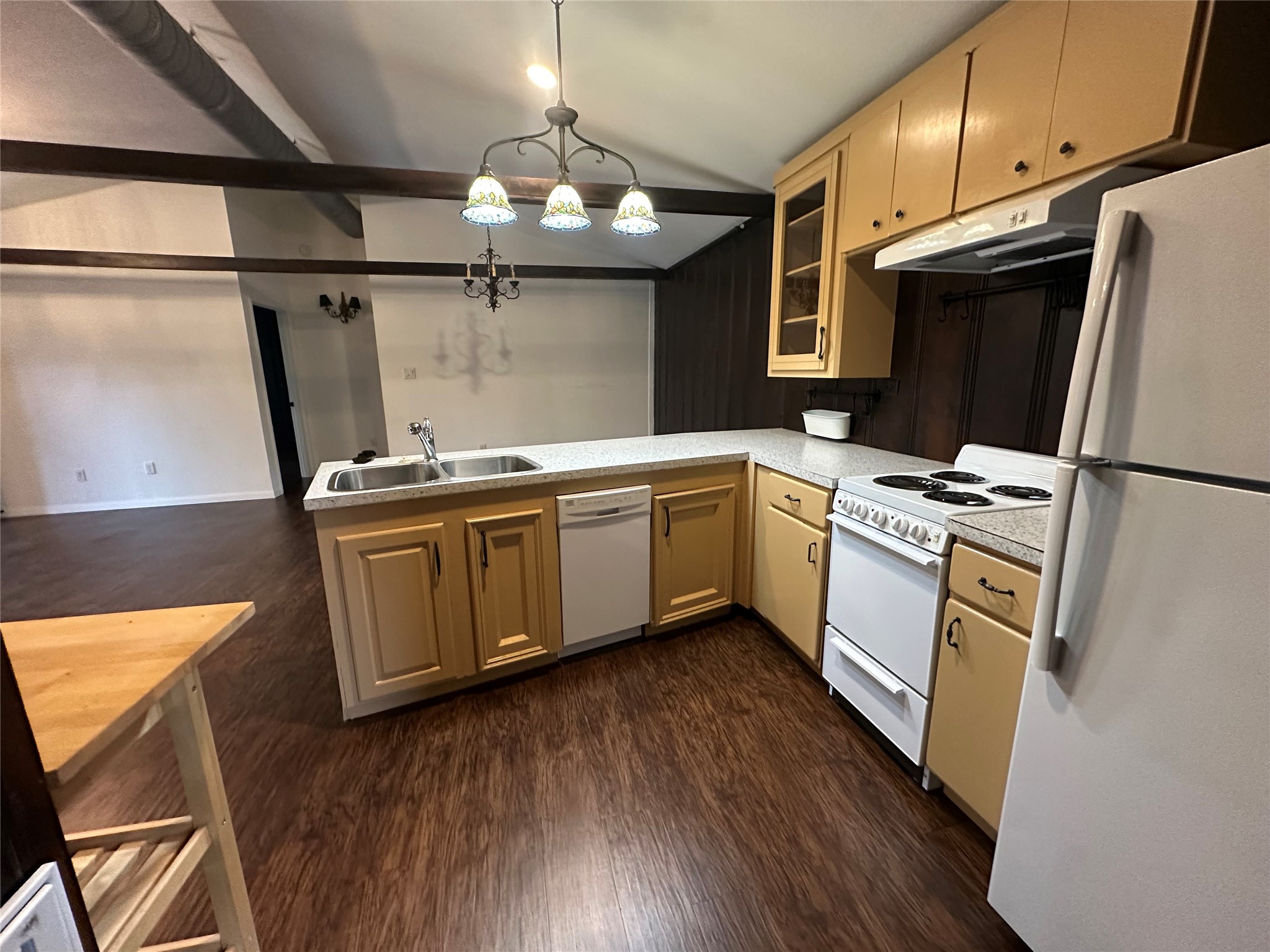 1604 Hailey Street, Unit B Conroe, TX 77301 - Photo 2 of 9 The efficient, open-concept kitchen features lovely light-toned cabinets, light-colored countertops, and white appliances including a stove/oven, dishwasher, and full-sized refrigerator, all under unique stained-glass pendant lights. It offers easy access to the adjacent dining/living space and is perfectly positioned for entertaining loved ones.