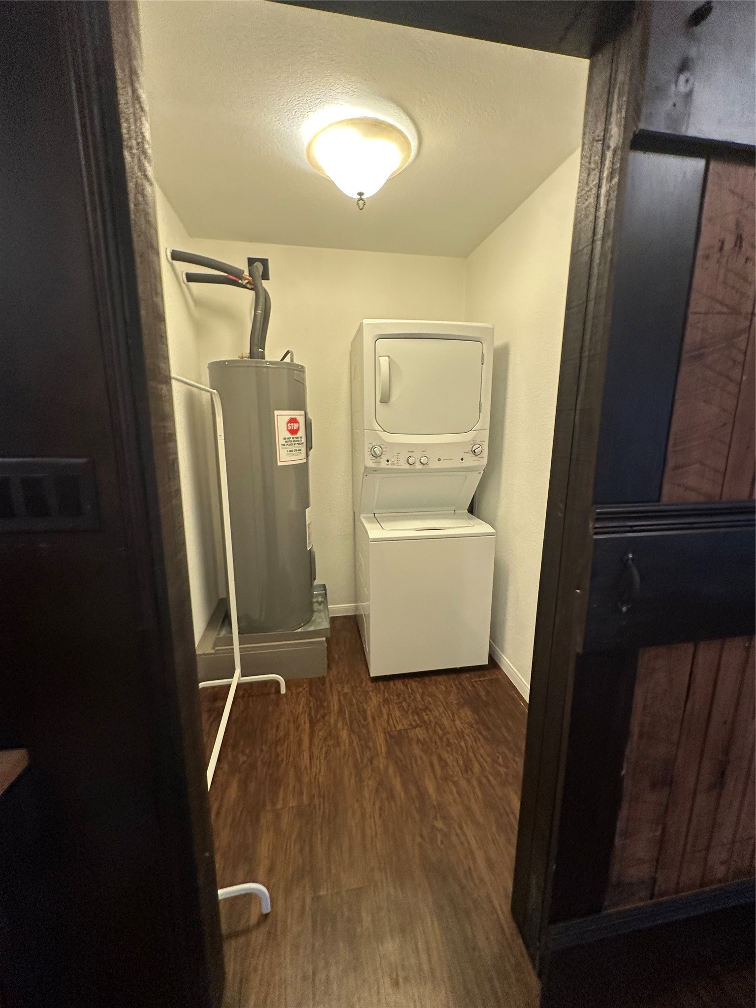 1604 Hailey Street, Unit B Conroe, TX 77301 - Photo 5 of 9 Tucked away behind a sliding barn-style door, this dedicated laundry and utility space features a stacked white washer and dryer unit and a water heater, maintaining organizational efficiency.