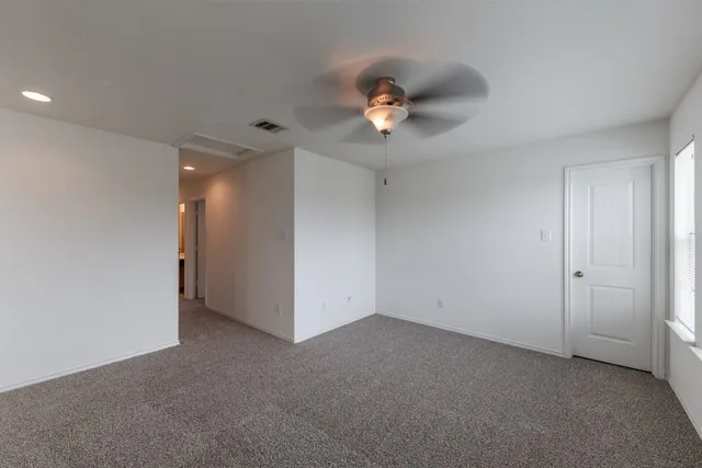 an empty room with a ceiling fan and a window