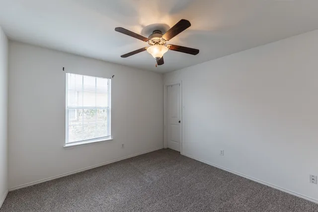 an empty room with a chandelier fan and a ceiling fan