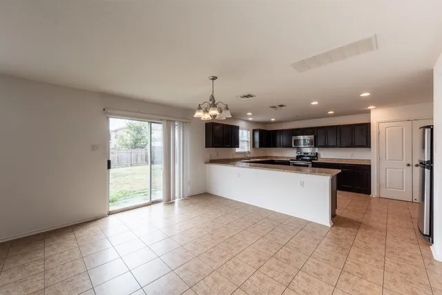 a view of kitchen with kitchen island granite countertop a stove a sink and a refrigerator