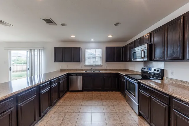 a large kitchen with granite countertop a stove top oven microwave and cabinets