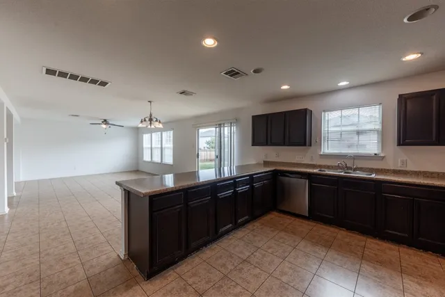a large kitchen with granite countertop a sink and cabinets