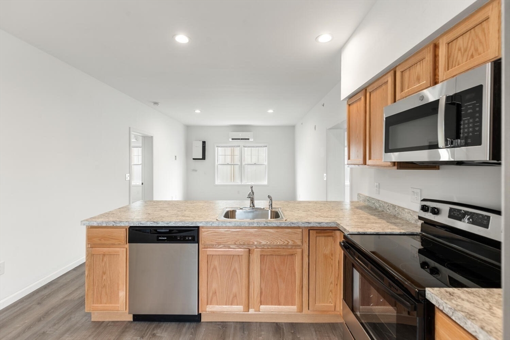 50 R Maplewood Avenue, Unit 215 Gloucester, MA 01930 - Photo 4 of 14 a kitchen with stainless steel appliances granite countertop a stove a sink and a microwave