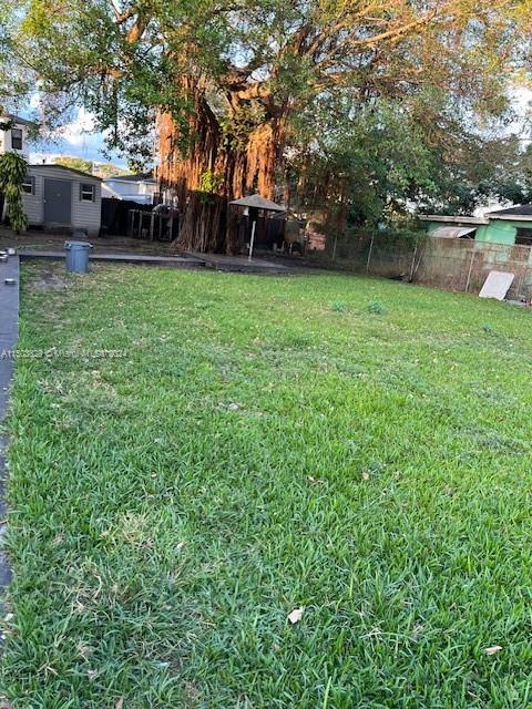 1755 Northwest 69th Street Miami, FL 33147 - Photo 8 of 36 a view of a patio with table and chairs with wooden fence and large trees
