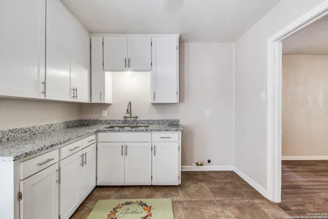 a kitchen with granite countertop white cabinets and white appliances