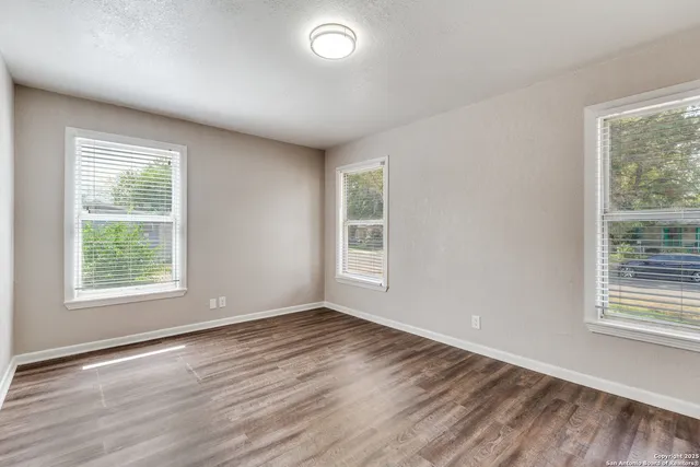 an empty room with wooden floor and windows