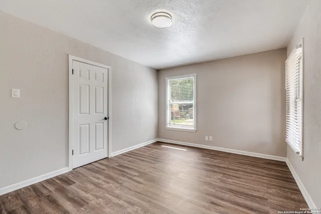 a view of empty room with wooden floor and fan