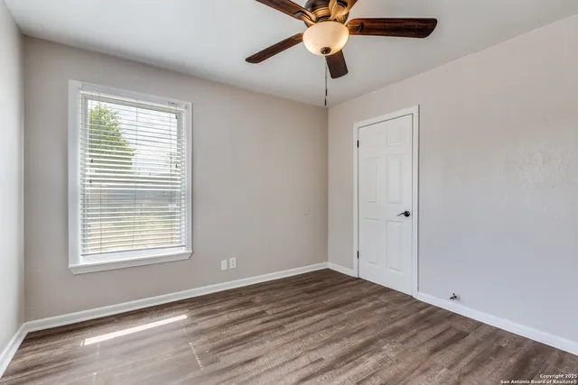 a view of an empty room with window and wooden floor