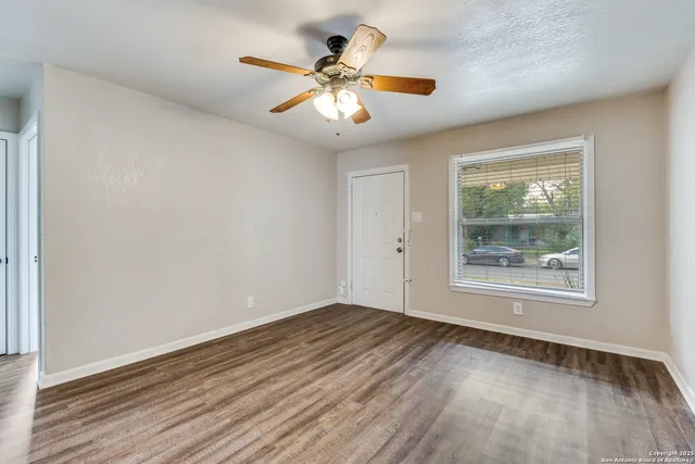 a view of an empty room with wooden floor and a window