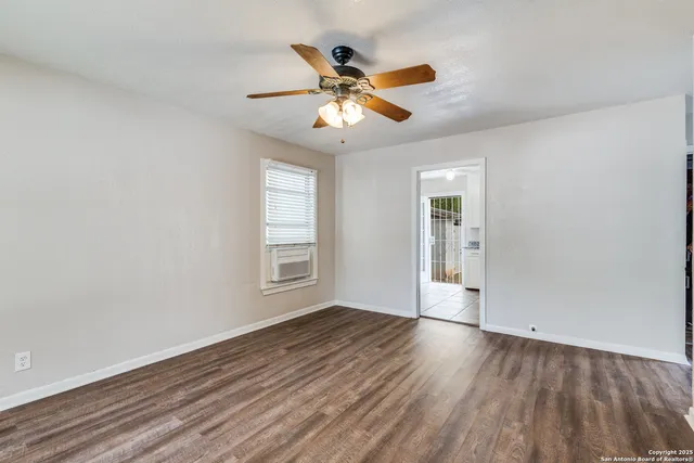 an empty room with wooden floor fan and windows
