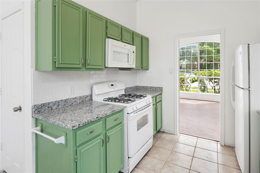 559 Raintree Circle Coppell, TX 75019 - Photo 15 of 40 Kitchen featuring vibrant green cabinetry, white subway tile backsplash, and speckled countertops