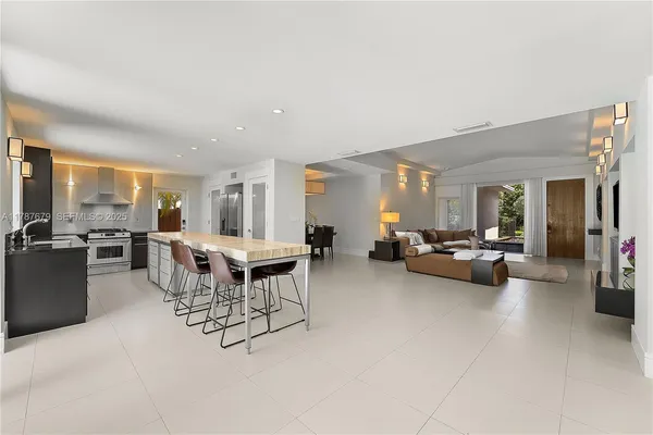 a living room with furniture and a dining table with projector the kitchen