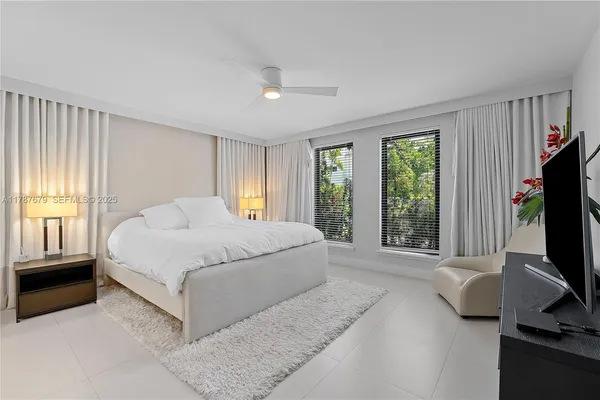 a bedroom with a bed flat screen tv and a window