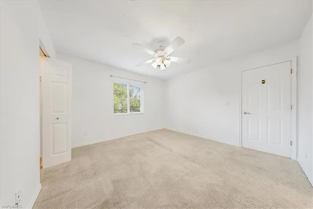 an empty room with a ceiling fan and a window