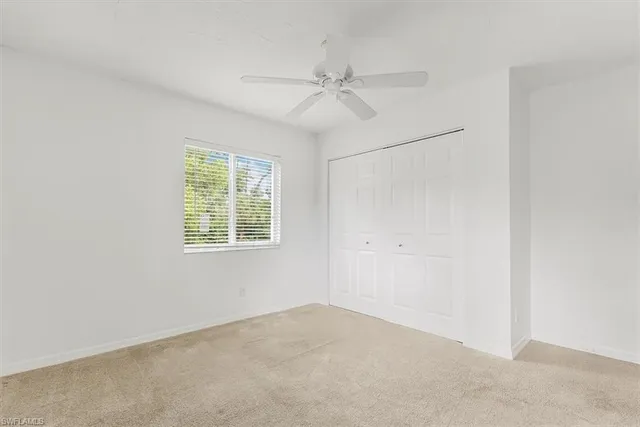 an empty room with a window and a fan
