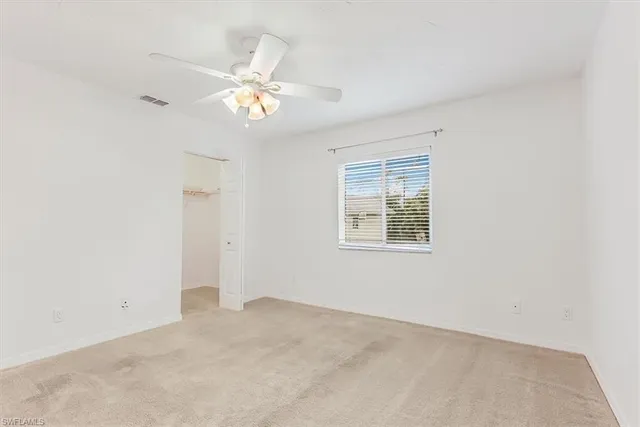 an empty room with a window and a chandelier fan