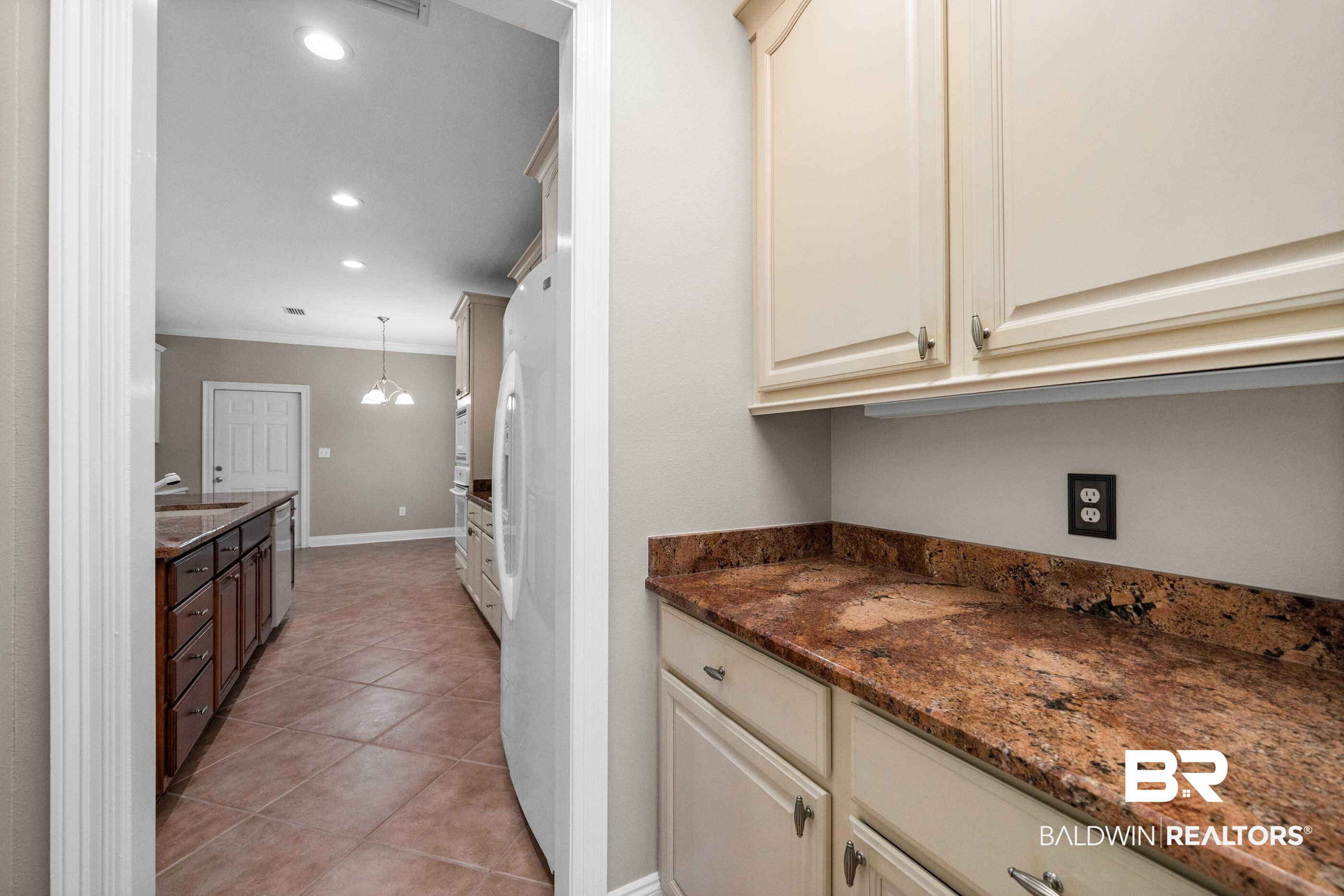 303 Savannah Circle Foley, AL 36535 - Photo 5 of 34 Kitchen area featuring light-toned cabinetry with dark hardware, brown speckled countertops, and an integrated refrigerator