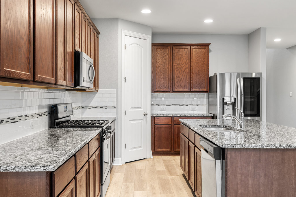 5208 Anaheim Avenue Pflugerville, TX 78660 - Photo 11 of 38 a kitchen with stainless steel appliances granite countertop a sink stove and refrigerator