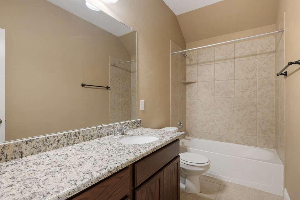5208 Anaheim Avenue Pflugerville, TX 78660 - Photo 30 of 38 a bathroom with a granite countertop sink a toilet and shower