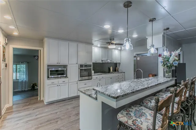 a kitchen with stainless steel appliances granite countertop a stove refrigerator and cabinets