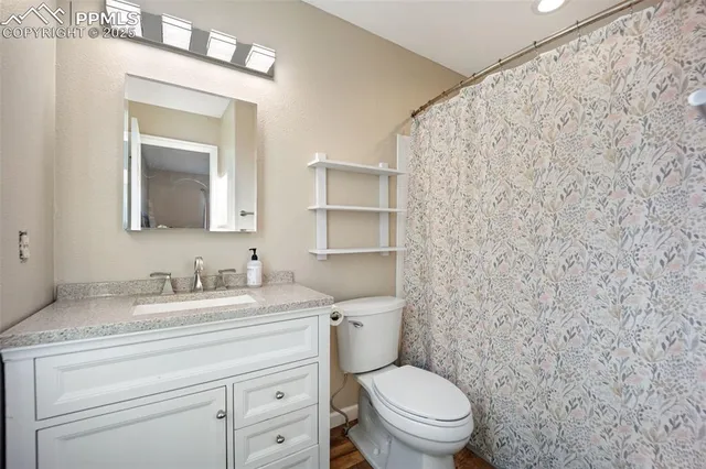 a bathroom with a granite countertop toilet sink and mirror