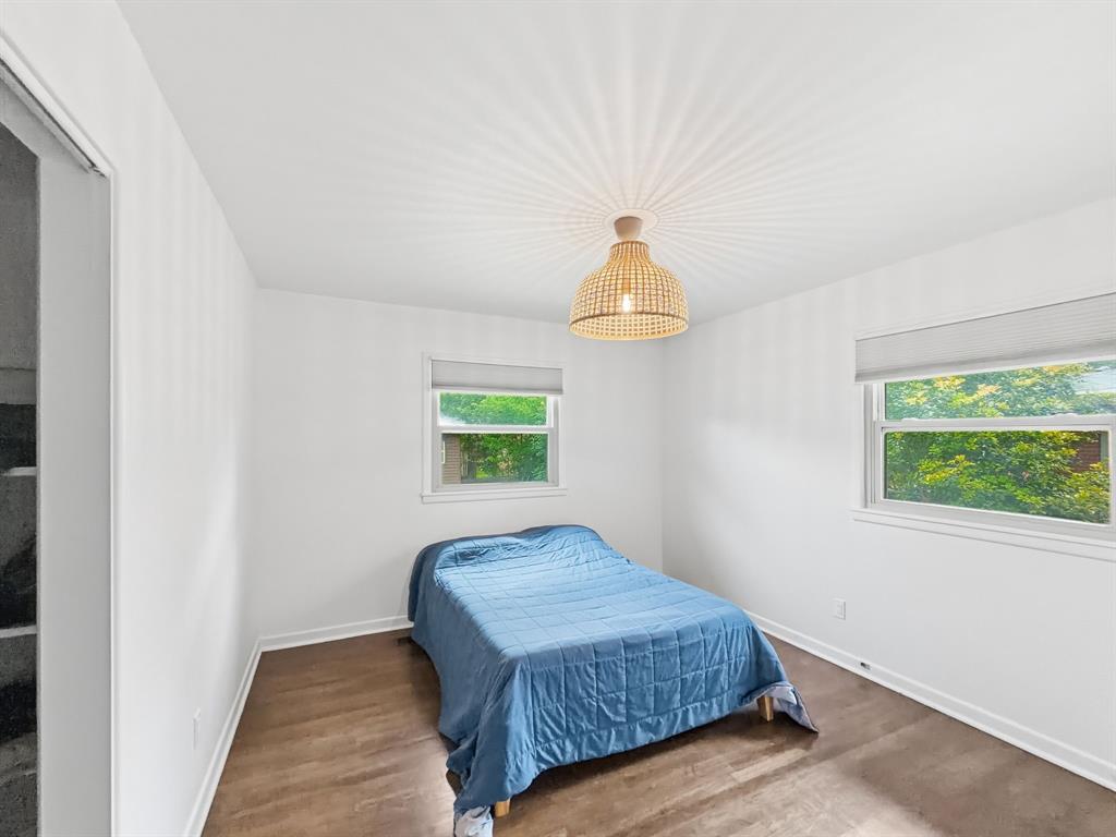 2137 Lenamon Street Waco, TX 76710 - Photo 10 of 29 Bright room featuring two windows with roller shades, wood-finish flooring, and a woven ceiling light fixture