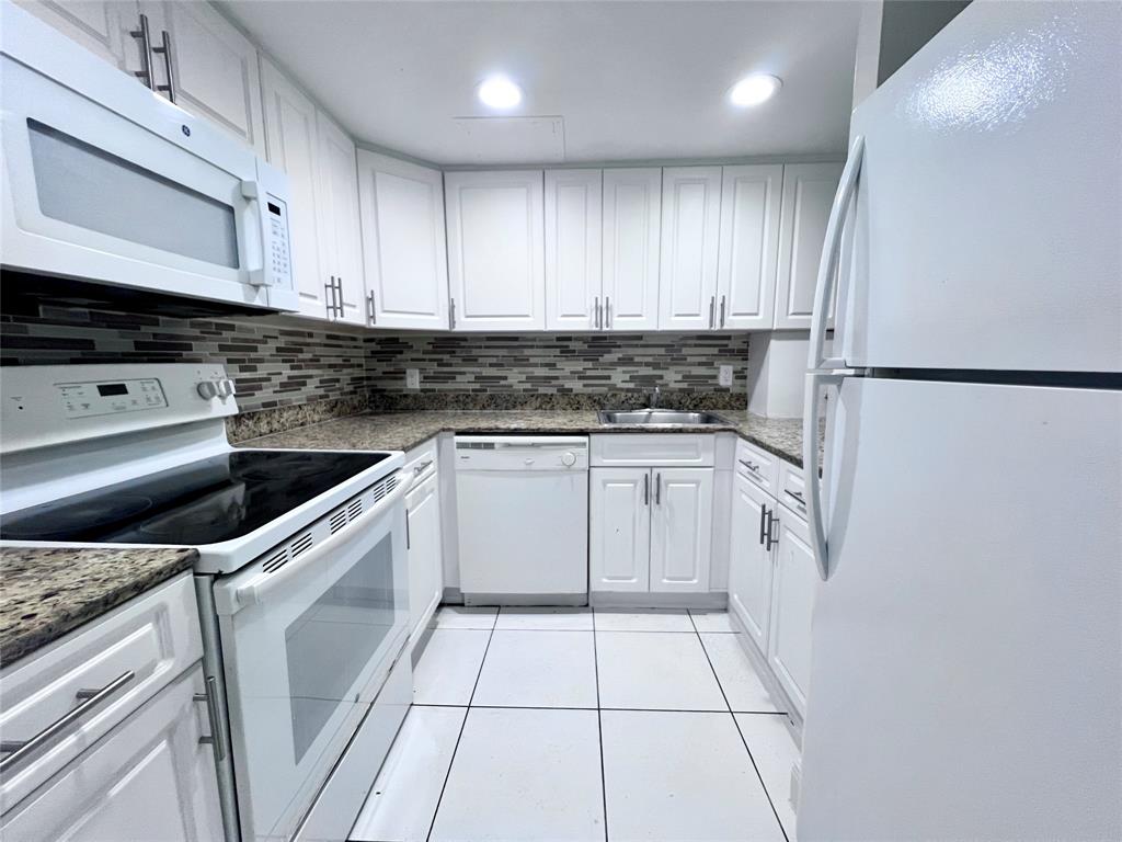 a kitchen with white cabinets and white appliances