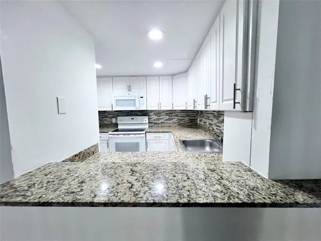 a kitchen with a white stove top oven and white cabinets