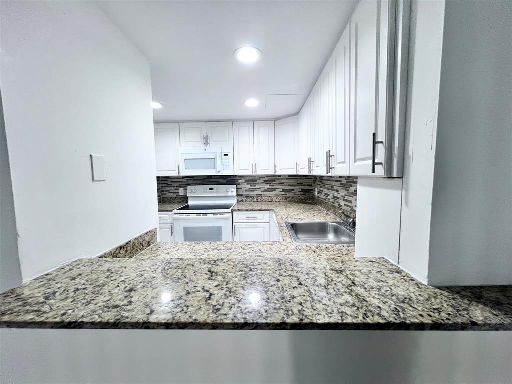 2580 Northwest 56th Avenue, Unit 700420 Lauderhill, FL 33313 - Photo 2 of 16 a kitchen with a white stove top oven and white cabinets