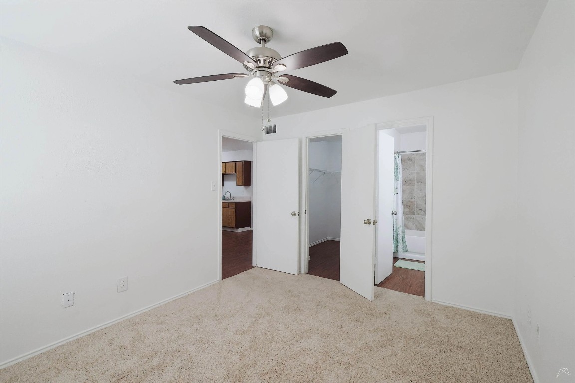 2323 Wells Branch Parkway, Unit C102 Austin, TX 78728 - Photo 10 of 20 Unfurnished bedroom with carpet floors, a spacious closet, ceiling fan, and connected bathroom
