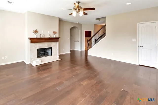 a view of an empty room with wooden floor fireplace and a window