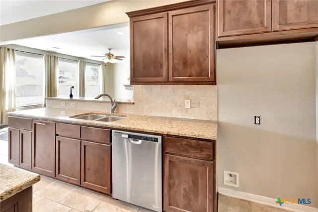 a kitchen with granite countertop cabinets stainless steel appliances a sink and a window