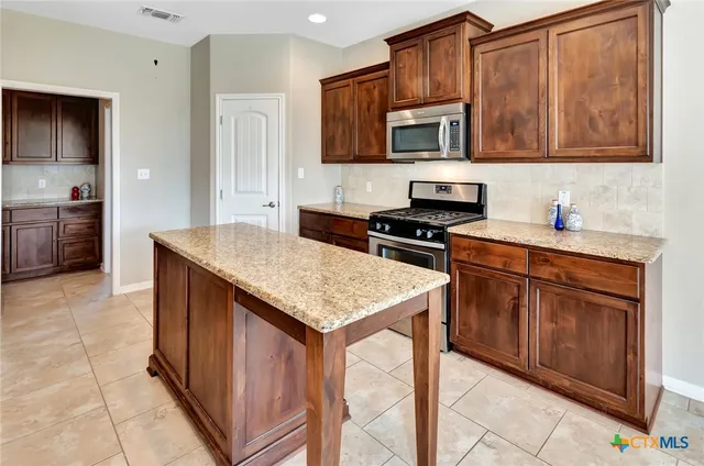 a kitchen with stainless steel appliances granite countertop a stove top oven a sink dishwasher and wooden cabinets