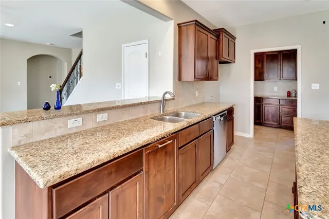 a kitchen with kitchen island granite countertop a sink and a wooden cabinets