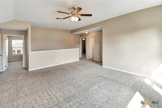 a view of a big room with carpet and a chandelier fan