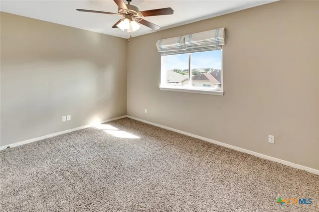 an empty room with a window and a fan