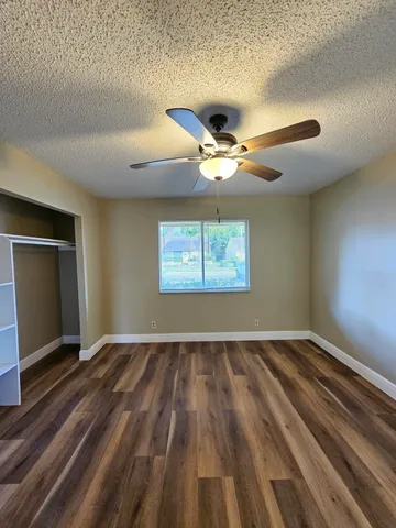 an empty room with wooden floor and a ceiling fan