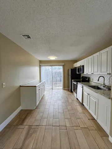 a large kitchen with stainless steel appliances granite countertop a stove a sink and a refrigerator