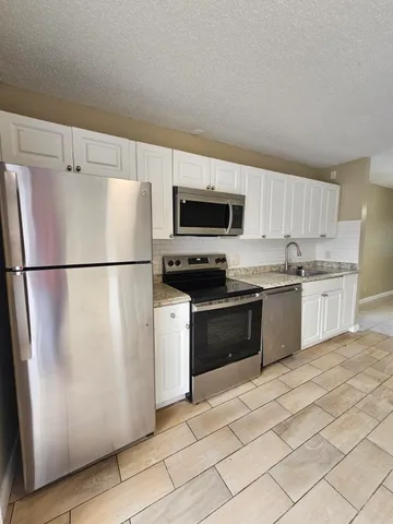 a kitchen with stainless steel appliances granite countertop a refrigerator stove a sink and a microwave