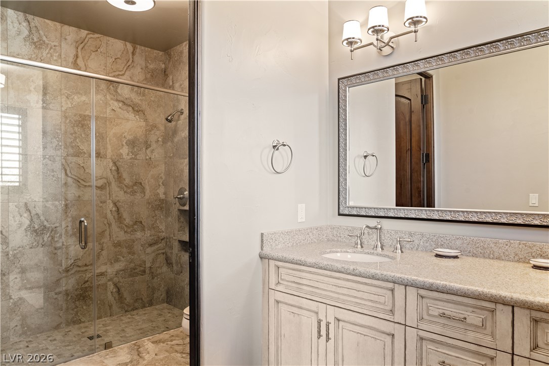 1123 Christian Road Henderson, NV 89002 - Photo 47 of 94 A refined vanity with stone counters and an elegant framed mirror complement a spacious, tiled walk-in shower.