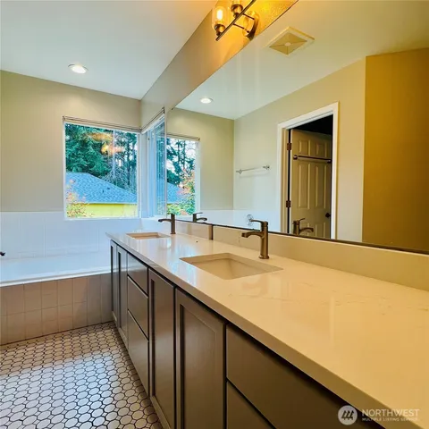 a bathroom with a sink a large mirror and a bathtub