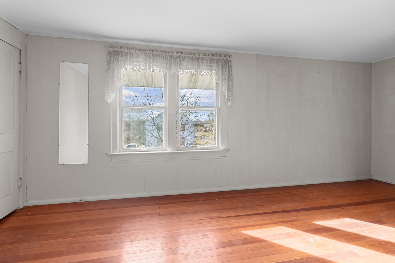 607 West Burbank Street Harvard, IL 60033 - Photo 13 of 22 a view of an empty room with wooden floor and a window