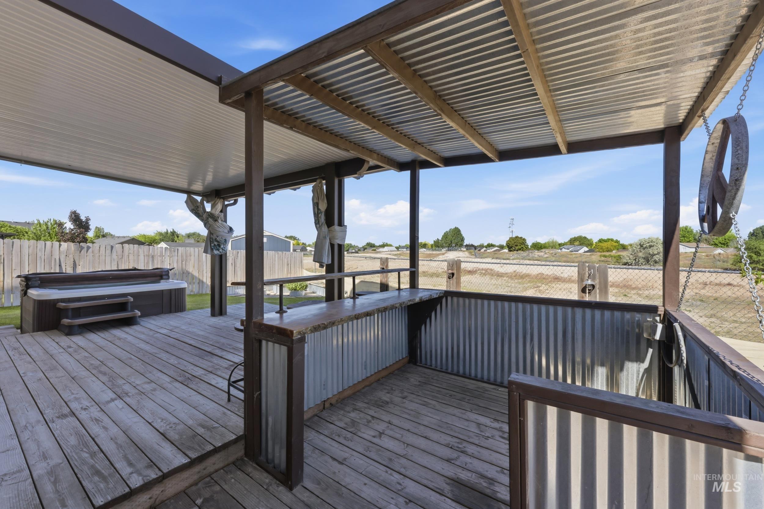 4855 South Chex Way Boise, ID 83709 - Photo 30 of 47 Spacious outdoor deck featuring a covered bar area with corrugated metal accents, a separate hot tub, and wood-finish flooring