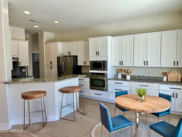 a kitchen with stainless steel appliances granite countertop a stove a sink a microwave a dining table and chairs