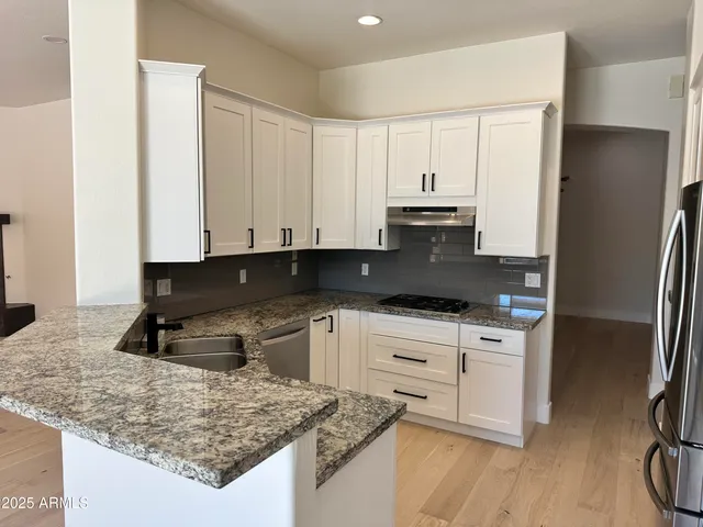 a kitchen with granite countertop a sink a stove and refrigerator